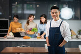 Young Asian Man Chef Wearing Apron with Two Women Preparing Food in the Kitchen.