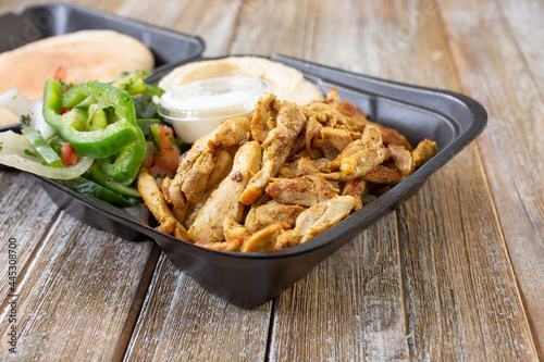 A closeup view of a chicken shawarma combo in a styrofoam to-go container.
