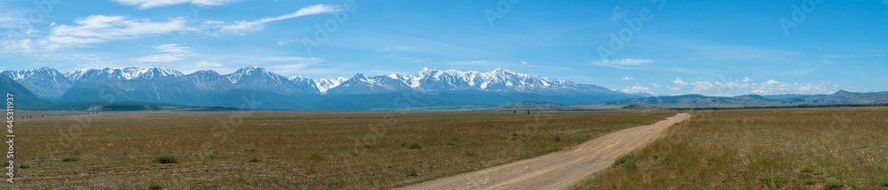 Panoramic view of the road going along the Kuraiskaya steppe against the background of the rocky snow-capped mountain slopes of the Chuisky ridge, Altai photo