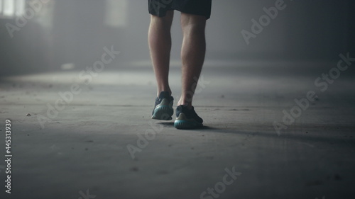 Male athlete feet walking in loft building. Man legs going for training