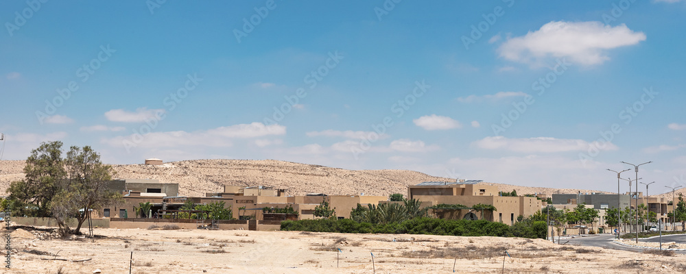 a modern desert town in the Negev in Israel where the construction is appropriate for the arid area showing undeveloped land and a water tank on the hill