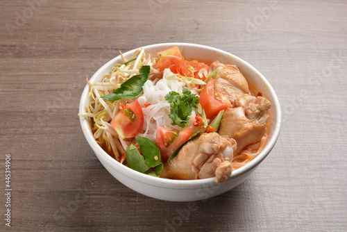 cook curry spicy chilli laksa soup with chicken meat, vegetable  and noodle on wood background asian halal menu