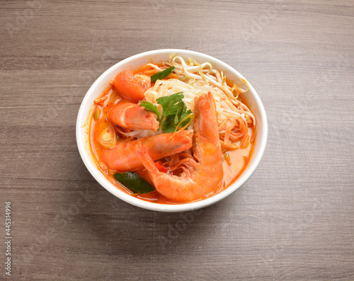 cook curry spicy chilli laksa soup with seafood prawn, vegetable and noodle on wood background asian halal menu