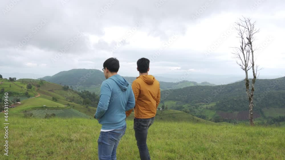 4K Two handsome Asian people man friends walking with talking together on mountain trail. Healthy male friendship enjoy outdoor activity and active lifestyle hiking and camping in summer vacation. 4K Two handsome Asian people man friends walking with talking together on mountain trail. Healthy male friendship enjoy outdoor activity and active lifestyle hiking and camping in summer vacation.