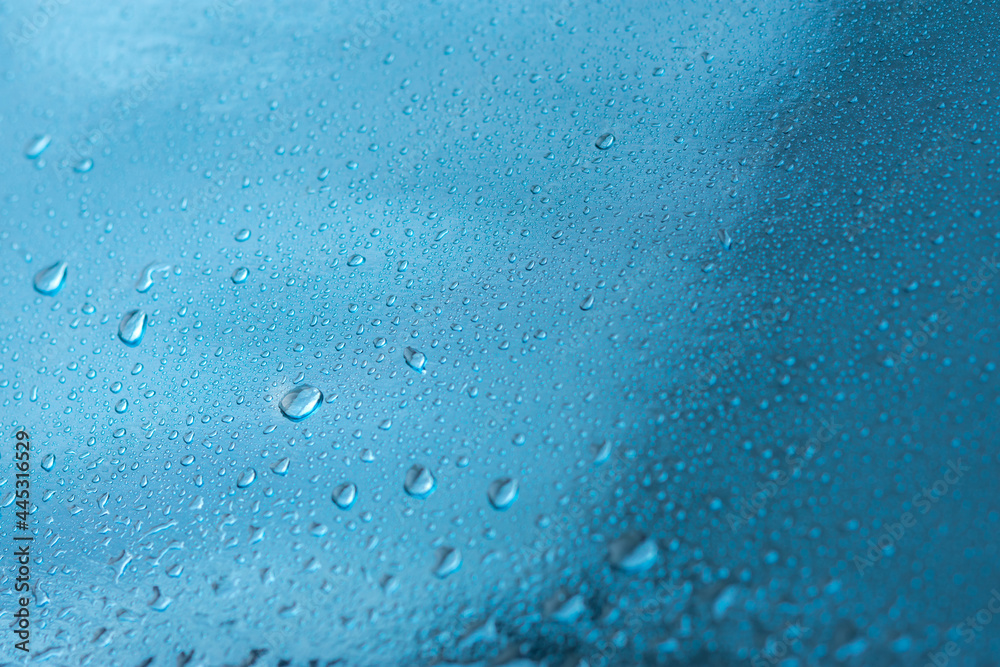 Obraz premium Abstract background with raindrops and beautiful blue bokeh. The concept of autumn and the cold stormy weather. Texture of macro drops on the blurred background of the window. Loneliness sadness