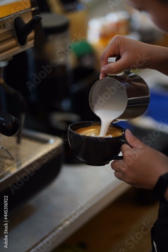 barista pouring milk to make cappuccino 