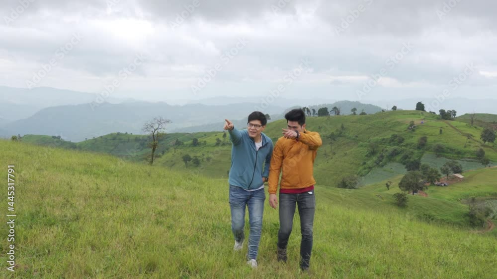 4K Two handsome Asian people man friends walking with talking together on mountain trail. Healthy male friendship enjoy outdoor activity and active lifestyle hiking and camping in summer vacation. 4K Two handsome Asian people man friends walking with talking together on mountain trail. Healthy male friendship enjoy outdoor activity and active lifestyle hiking and camping in summer vacation.