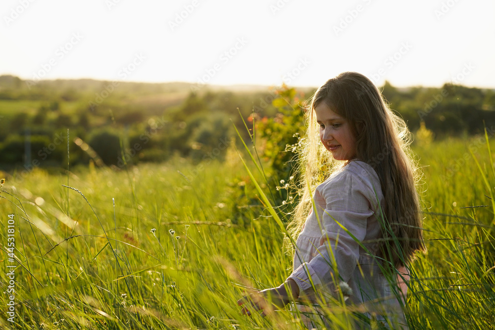 Portrait of cute smiling caucasian girl walking on the meadow and holding a bouquet of wildflowers. Summer sunset. Happy Childhood concept. Nature background. Copy space. Portrait of cute smiling caucasian girl walking on the meadow and holding a bouquet of wildflowers. Summer sunset. Happy Childhood concept. Nature background. Copy space.