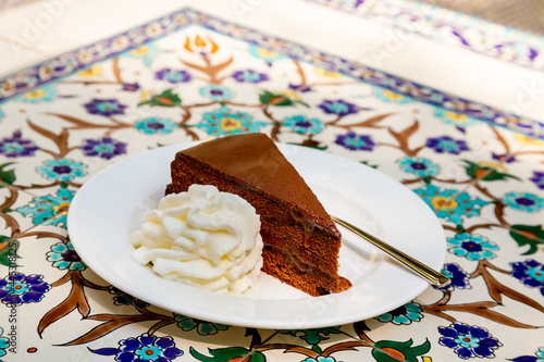 Apricot and chocolate Sacher cake with whipped cream. Sachertorte is a chocolate cake, or torte of Austrian origin, invented by Franz Sacher supposedly in 1832 for Prince Metternich in Vienna photo
