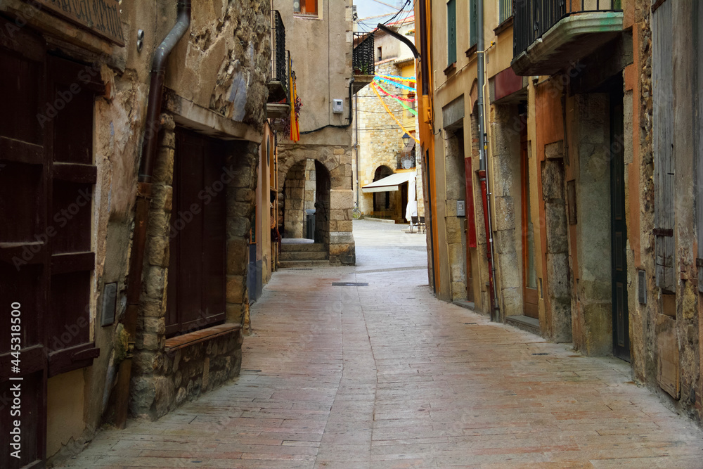 Traditional european cityscape - ancient gothic quarter with a cobbled narrow winding street and overhanging walls of houses in Besalu, Girona, Catalonia, Spain, South Europe