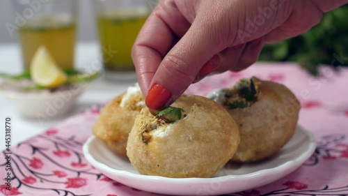 Indian chef's hand decorating delicious Golgappas with fresh mint leaves - Street food from India. Closeup shot Pudina water  Aloo Bhujia  sliced green chilies  onions  and lemons - Gol Gappa/ photo