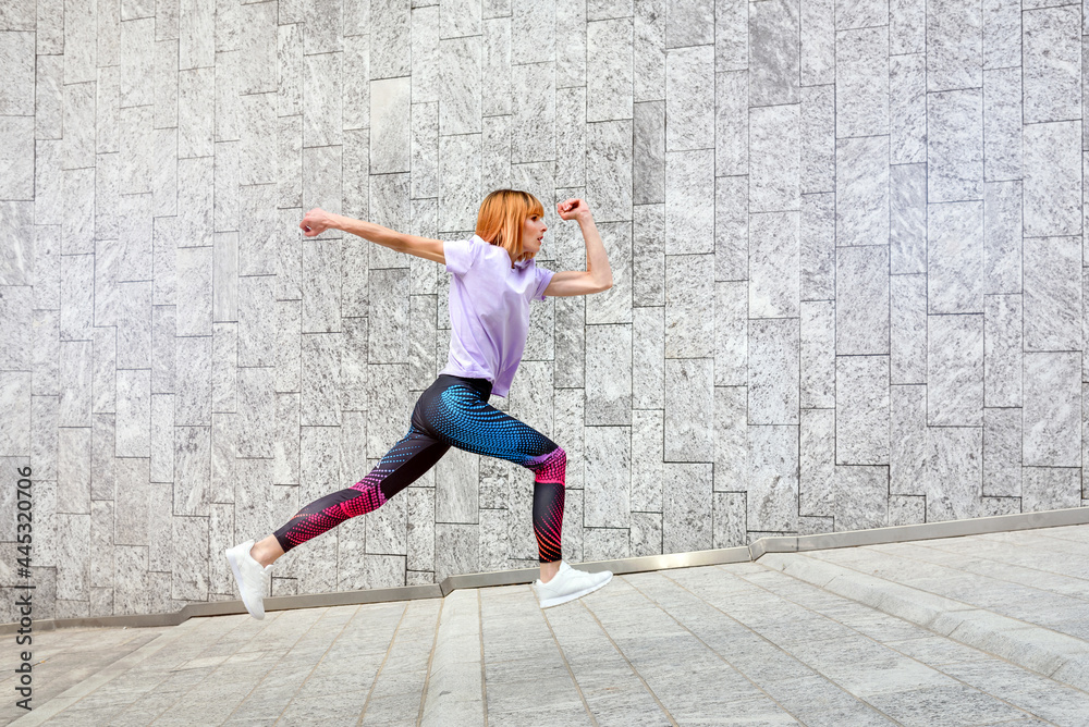 Sporty woman jogging through town running up an incline Sporty woman jogging through town running up an incline
