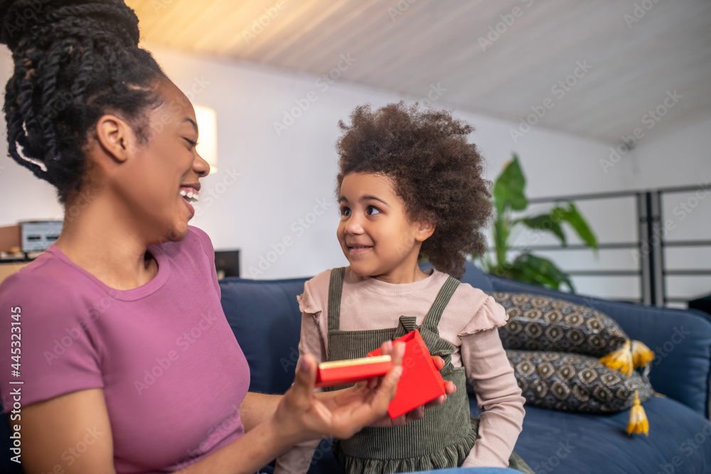 Laughing joyful mom with open box and looking daughter