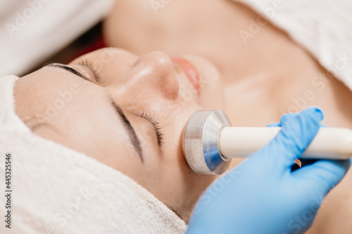 closeup people using Ultrasonic massage device for Facial Lifting Activate Collagen and Skin Tightening in beauty salon spa.