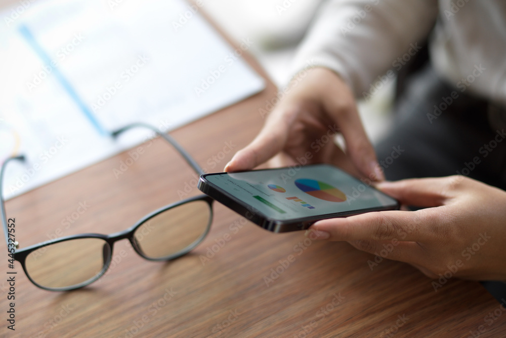 Fototapeta premium Close up of female looking on financial chart on her smartphone