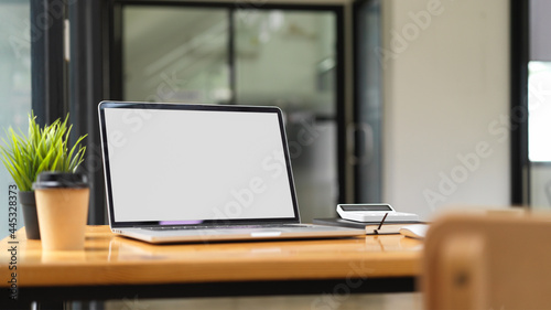 Laptop mock up with office supplies with office interior in the background, working space concept © bongkarn