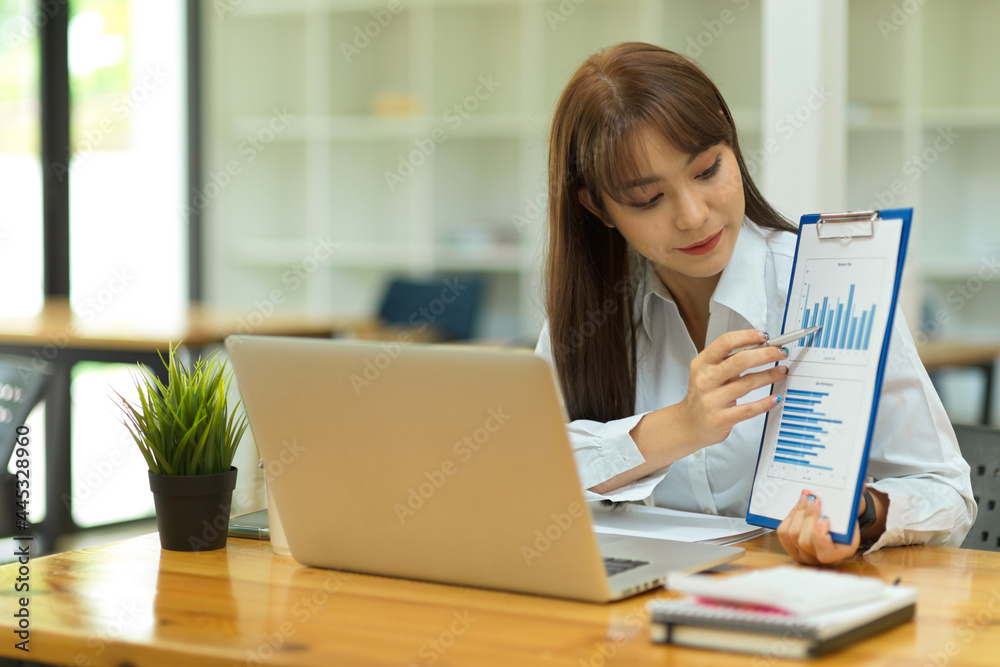 Portrait of attractive business female showing financial bar graph report on online meeting via laptop Portrait of attractive business female showing financial bar graph report on online meeting via laptop