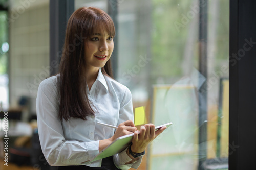 Portrait of businesswoman taking note on portable tablet with stylus pen © bongkarn
