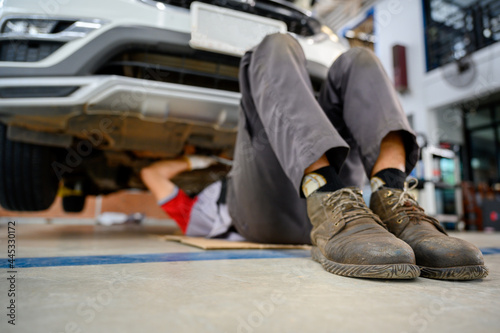 auto repair service sleep under the car Check the car suspension with rebar during balance adjustment. Align the car suspension at the auto repair station.