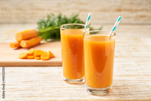 Fresh carrot juice in glasses on a white wooden table, selective focus.