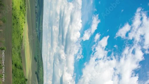 Timelapse of clouds over a field and forest on a summer day, vertical video