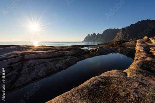 Midnight sun over scenic cliffs of Tungeneset on Senja island in northern Norway at a warm calm summer night