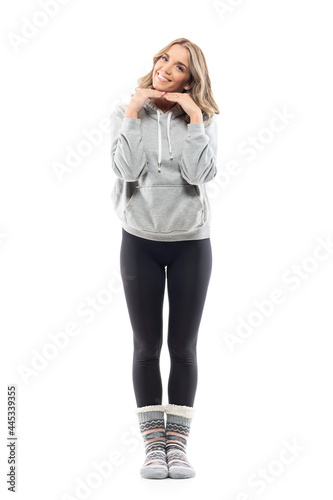 Beautiful young cute woman with perfect white toothy smile posing with hands under chin. Full body isolated on white background.