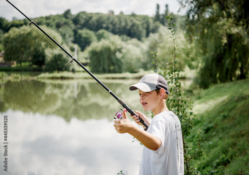 A boy holding a fishing rod and fishing in the lake, summer activities and hobbies for children A boy holding a fishing rod and fishing in the lake, summer activities and hobbies for children