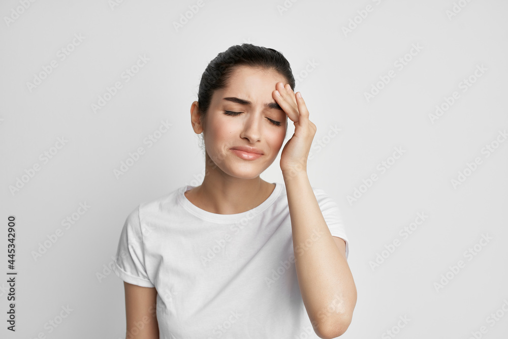 brunette in a white t-shirt holding her head migraine stress depression brunette in a white t-shirt holding her head migraine stress depression