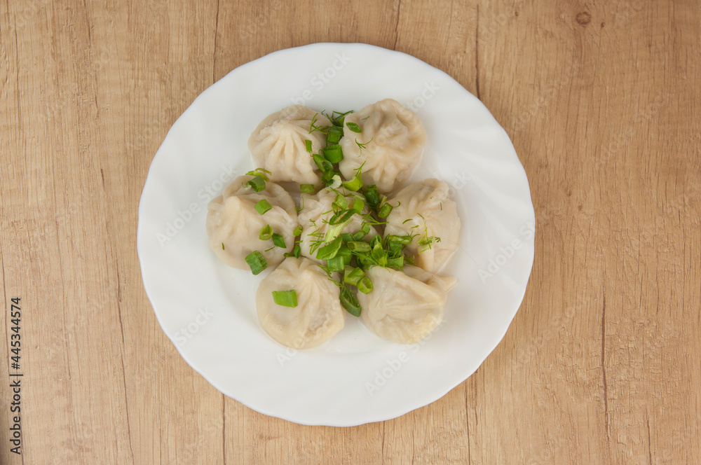 khinkali on a white plate with green onions khinkali on a white plate with green onions