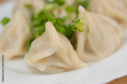 khinkali on a white plate with green onions