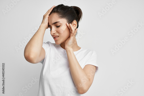 Woman in white t-shirt holding her head dissatisfied with health problems © SHOTPRIME STUDIO