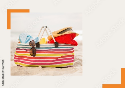 Photograph of bag with accessories at the beach against grey background