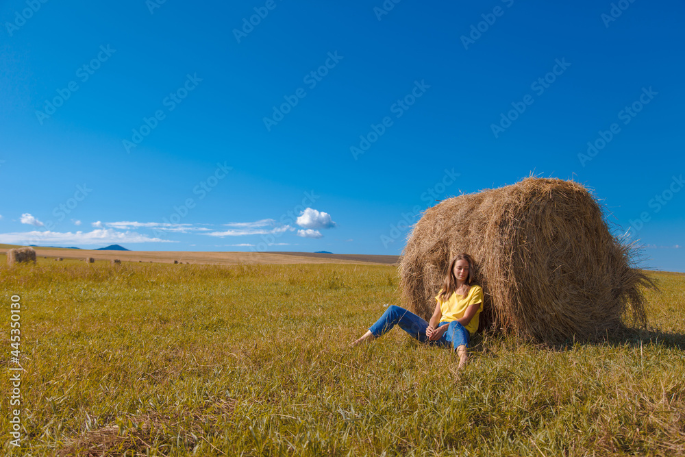 a girl is sunbathing in the hay. village life: harvesting hay for the winter. animal feed. a girl is sunbathing in the hay. village life: harvesting hay for the winter. animal feed.