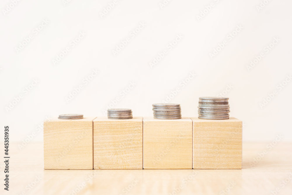 Blank wooden blocks with rising stacks of coins on table as concept of successful money investment and savings close view Blank wooden blocks with rising stacks of coins on table as concept of successful money investment and savings close view