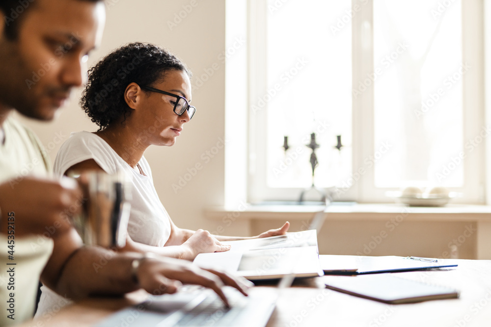 Obraz premium Middle eastern man and woman reading book and working with laptop