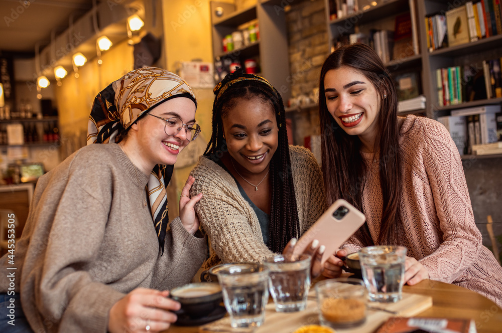 Three young multiethnic female friends spending time together at a coffee shop.