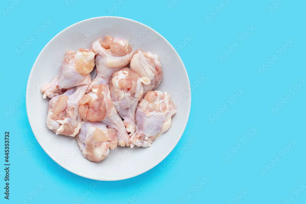 Fresh raw chicken wings (wingstick) in white plate on blue background. Fresh raw chicken wings (wingstick) in white plate on blue background.