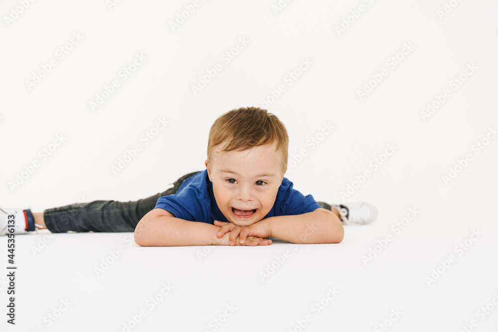 Boy with down syndrome smiling while lying on floor Boy with down syndrome smiling while lying on floor