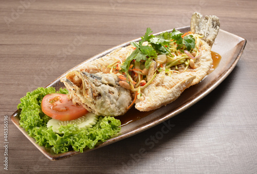 deep fried crispy whole grouper fish with mango salad dressing on wood background asian halal menu