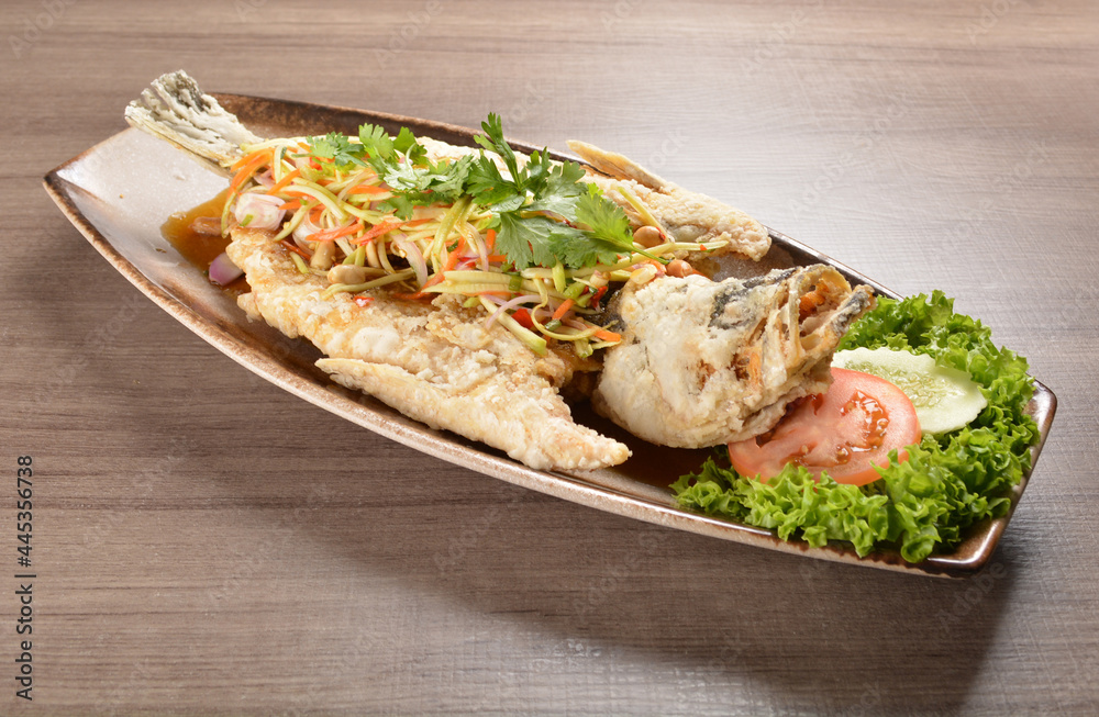 deep fried crispy whole grouper fish with mango salad dressing on wood background asian halal menu deep fried crispy whole grouper fish with mango salad dressing on wood background asian halal menu