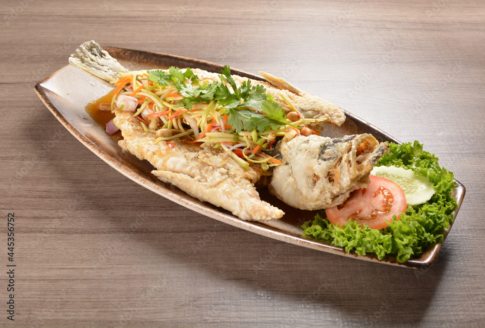 deep fried crispy whole grouper fish with mango salad dressing on wood background asian halal menu deep fried crispy whole grouper fish with mango salad dressing on wood background asian halal menu