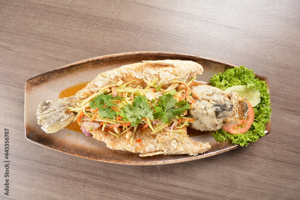 deep fried crispy whole grouper fish with mango salad dressing on wood background asian halal menu deep fried crispy whole grouper fish with mango salad dressing on wood background asian halal menu