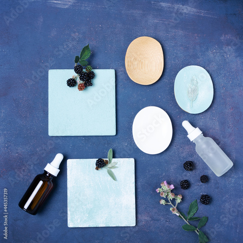 Cosmetic concept with serum and berries on dark blue background.  photo