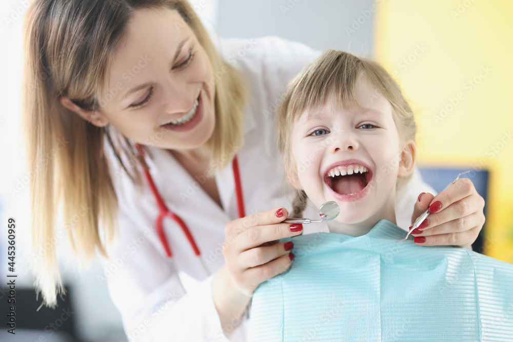 Dentist doctor examining teeth of little girl using instruments in clinic Dentist doctor examining teeth of little girl using instruments in clinic