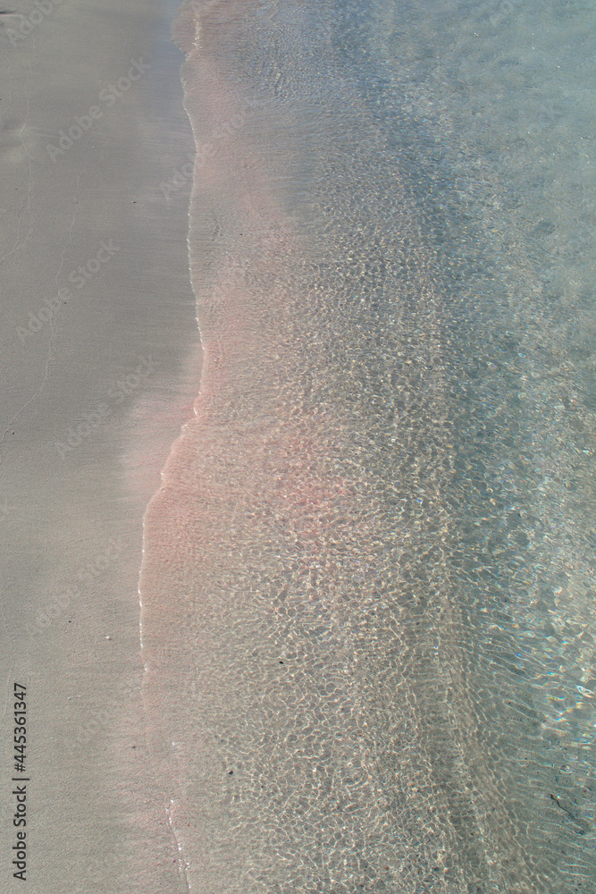 Abstract background of a beautiful sandy beach with azure transparent water and pink sand.