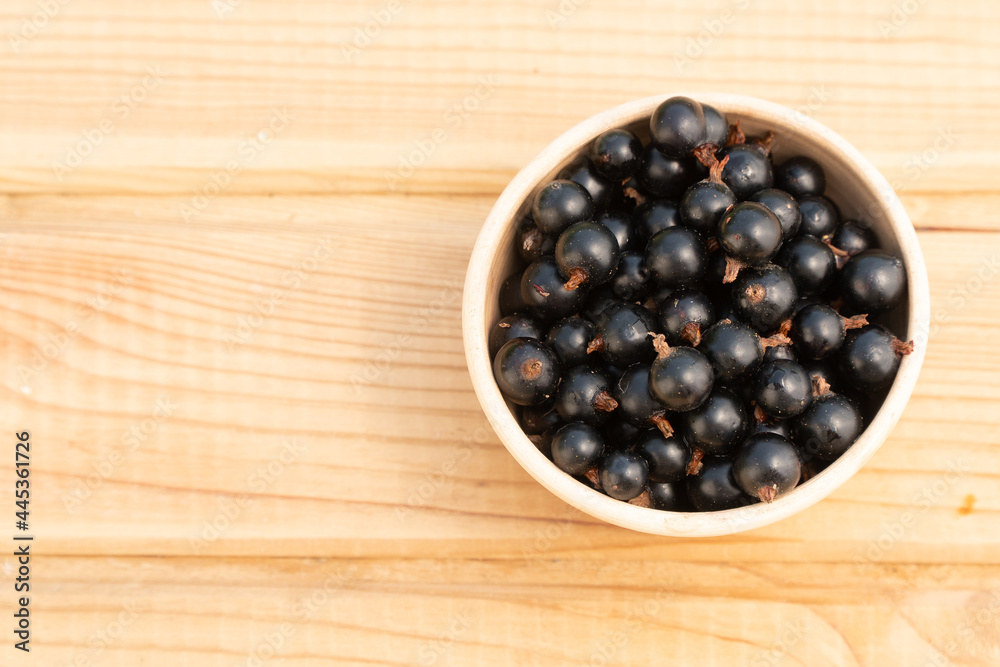 black currant berries in a clay plate. black currant on a wooden table black currant berries in a clay plate. black currant on a wooden table