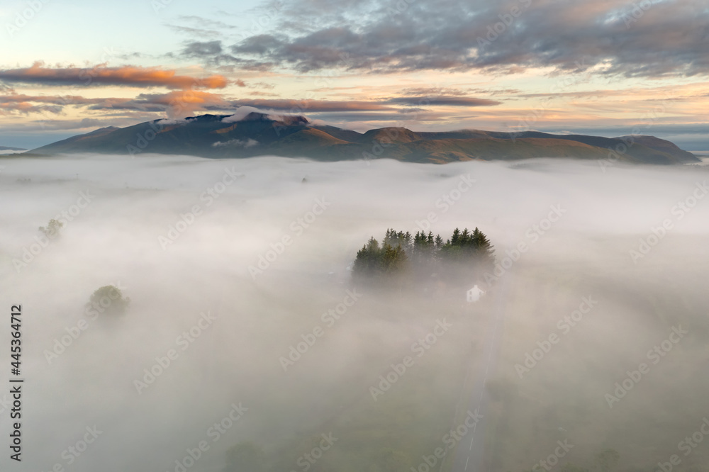 Breathtaking scenic view of misty valley in morning fog. Lake District, UK. Majestic British landscapes. Aerial drone photography.