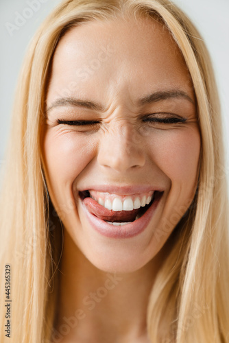 Young blonde woman smiling while licking her teeth