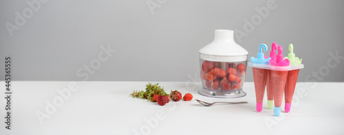 Form for ice cream and blender with strawberries on a white table on a gray background. Summer season of vitamins. Banner